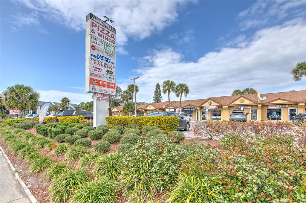 A strip mall features a tall directory sign and several small businesses under a roof — 1402 E FLETCHER AVENUE UNIT 1406, TAMPA, FL