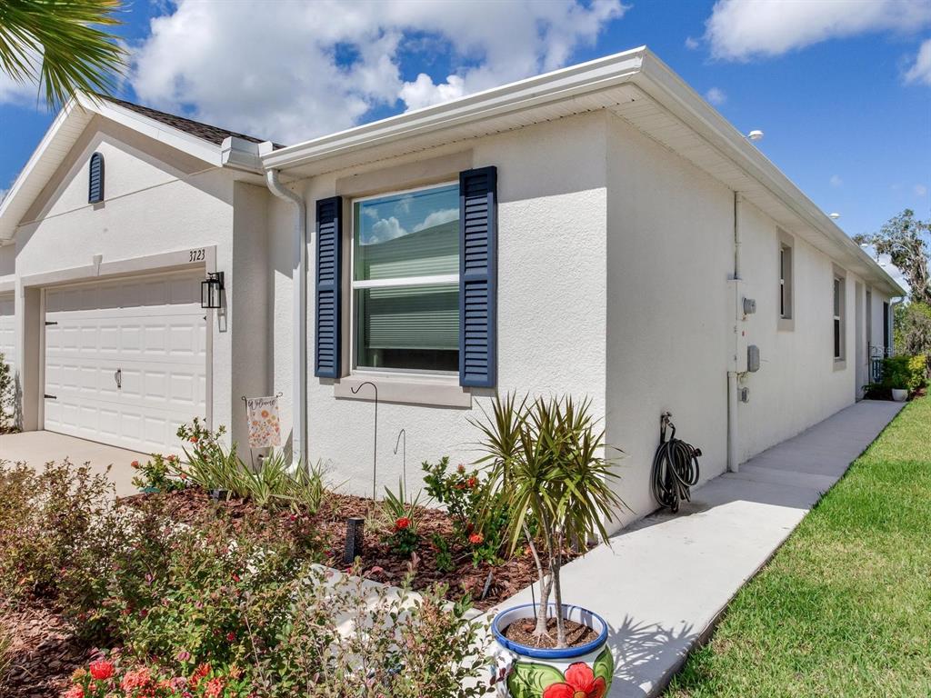 The exterior of a single-story home features a garage, blue shutters, and a concrete walkway — 3723 STORMY THISTLE PLACE, PLANT CITY, FL