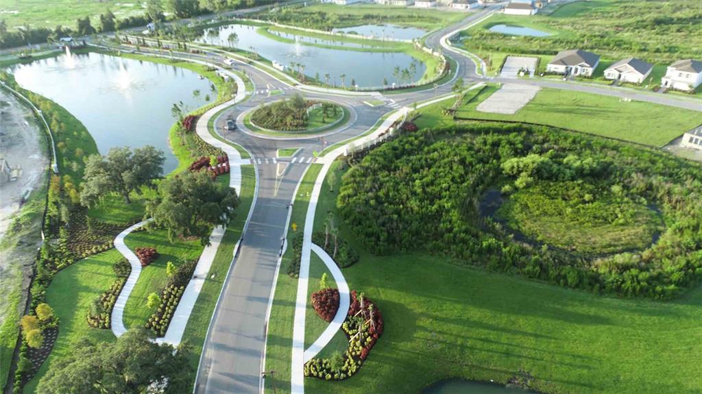 An aerial view shows a roundabout, landscaped ponds, green spaces, and nearby residential houses — 3723 STORMY THISTLE PLACE, PLANT CITY, FL