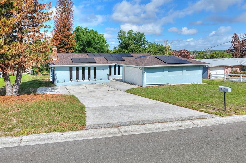 A light blue, single-story house with solar panels on the roof and a concrete driveway — 1147 CIRCLE DRIVE, LAKE WALES, FL