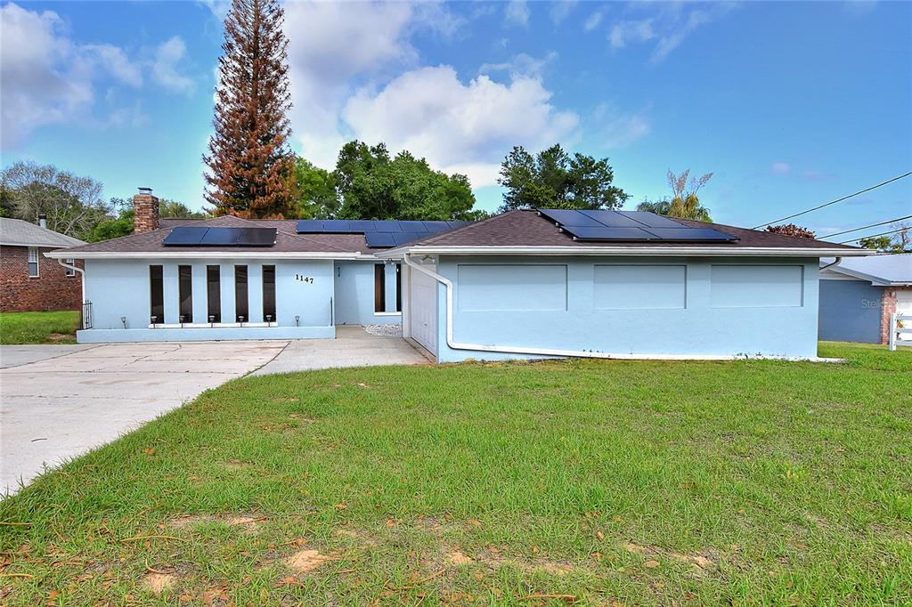 A light blue single-story house with solar panels on the roof and a concrete driveway — 1147 CIRCLE DRIVE, LAKE WALES, FL