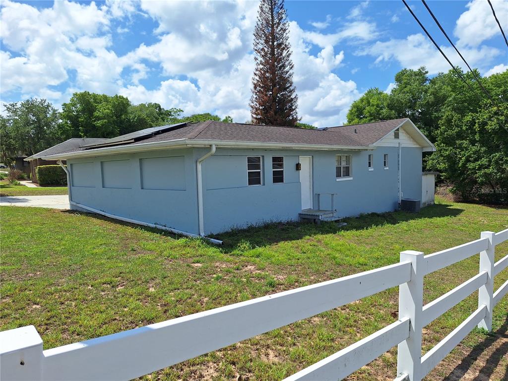 A light blue, single-story house with a dark shingled roof and a white fence — 1147 CIRCLE DRIVE, LAKE WALES, FL