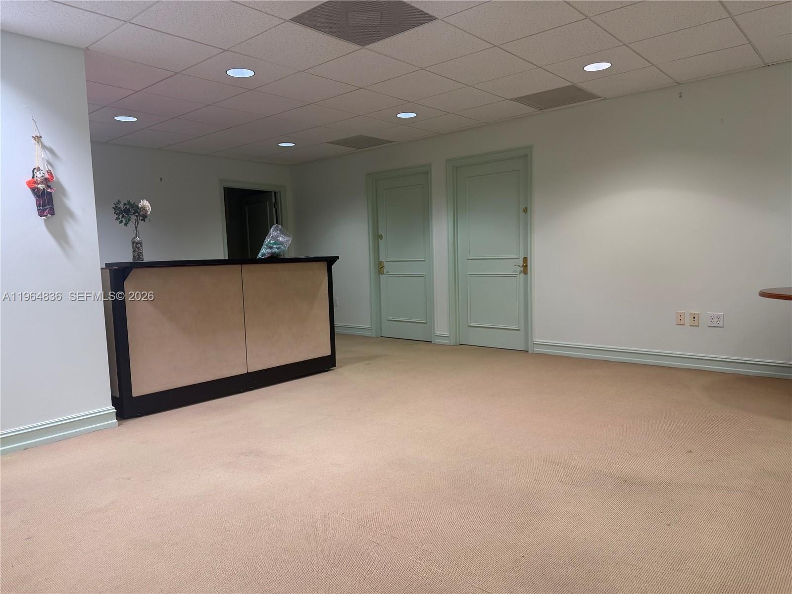 An office space features a reception desk, two light green doors, and beige carpeting — 2435 Hollywood Blvd, Hollywood FL 33020, HOLLYWOOD, FL