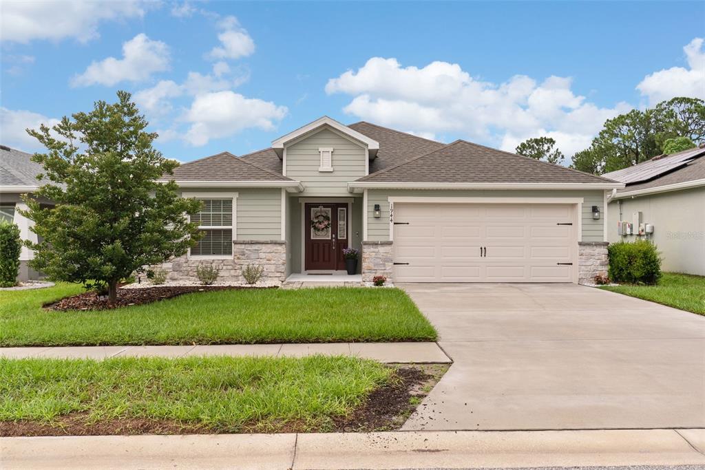 A single-story house with light green siding, stone accents, and a two-car garage — 1944 HARVEST LANDING CIRCLE, LAKELAND, FL