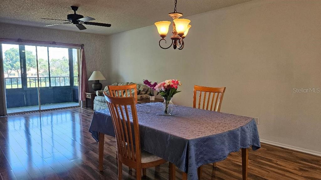 A dining area features a table with a blue cloth, wooden chairs, and a chandelier — 5920 80TH STREET N UNIT 308, ST PETERSBURG, FL