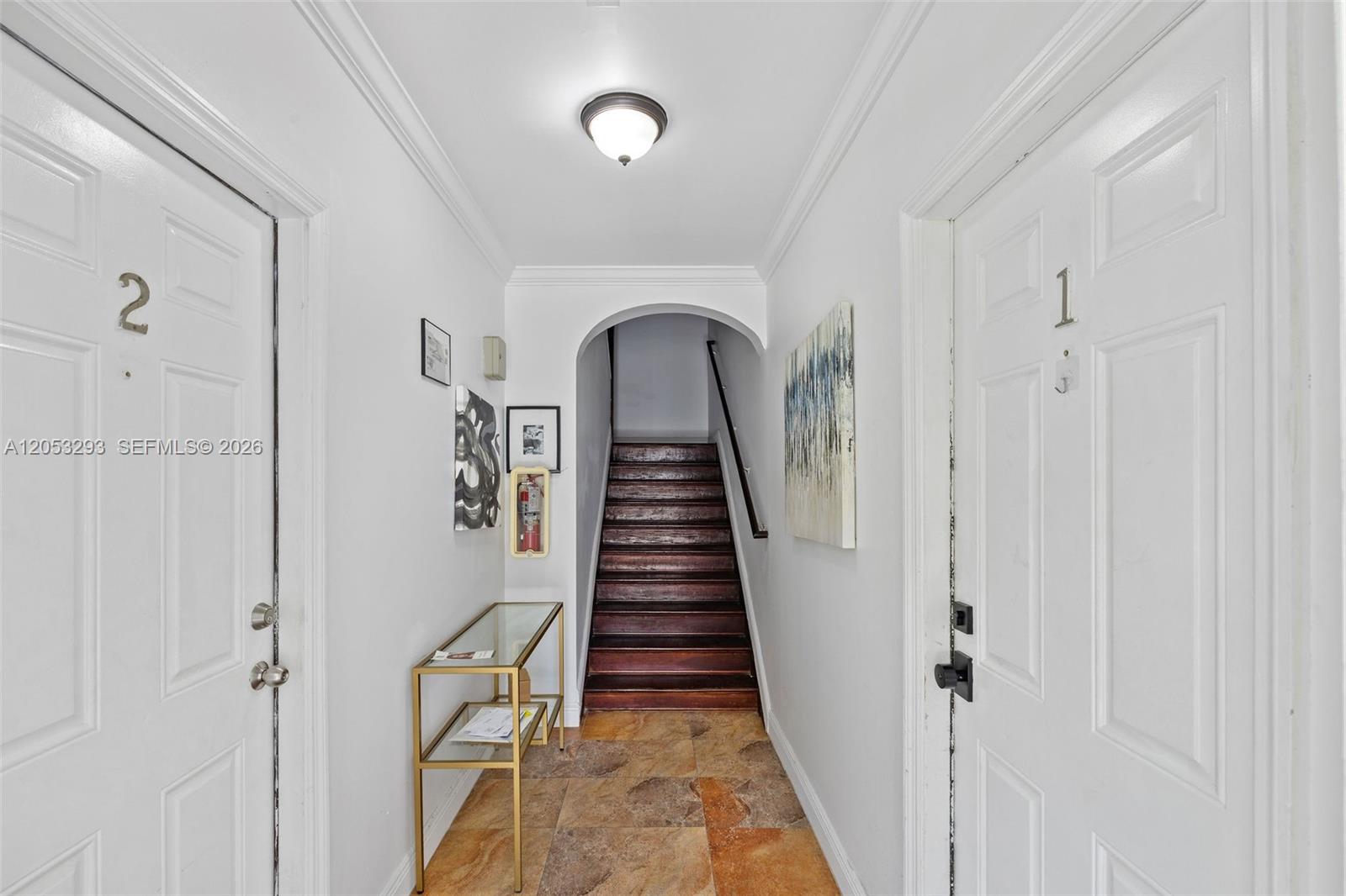 A hallway features two white doors, a glass console table, and wooden stairs — 417 NE 26th St # 5, Miami FL 33137, MIAMI, FL