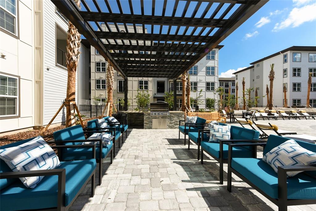 An outdoor patio area features a pergola, stone grill station, and blue cushioned seating — 6629 DAN DICIOLLA DRIVE UNIT C1-TH, WILDWOOD, FL