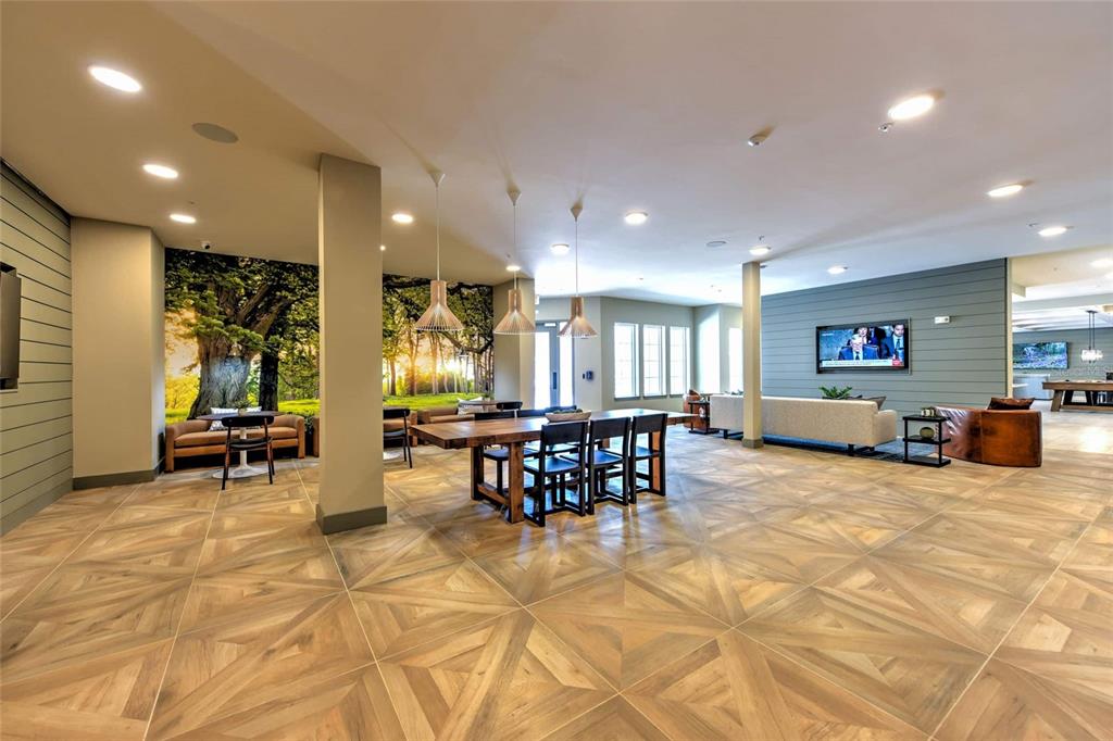 A spacious community lounge features wood-look tile flooring, a dining table, and a wall mural — 6629 DAN DICIOLLA DRIVE UNIT C1-TH, WILDWOOD, FL