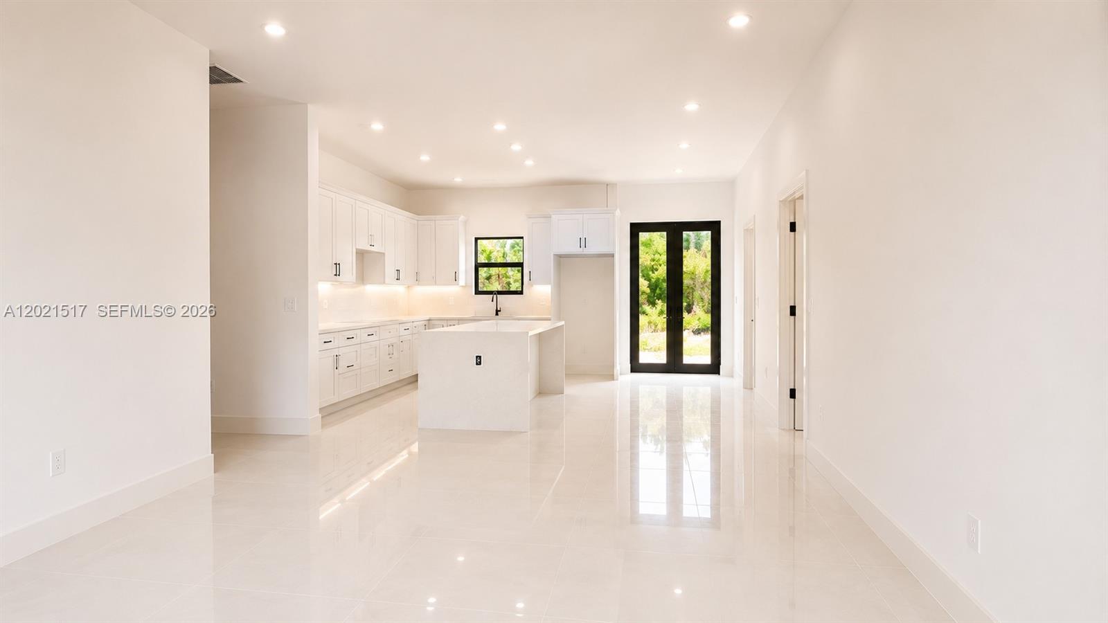 A modern white kitchen features a central island, glossy tile floors, and black-framed glass doors — 703 LONG ISLAND, Lehigh Acres FL 33974, LEHIGH ACRES, FL