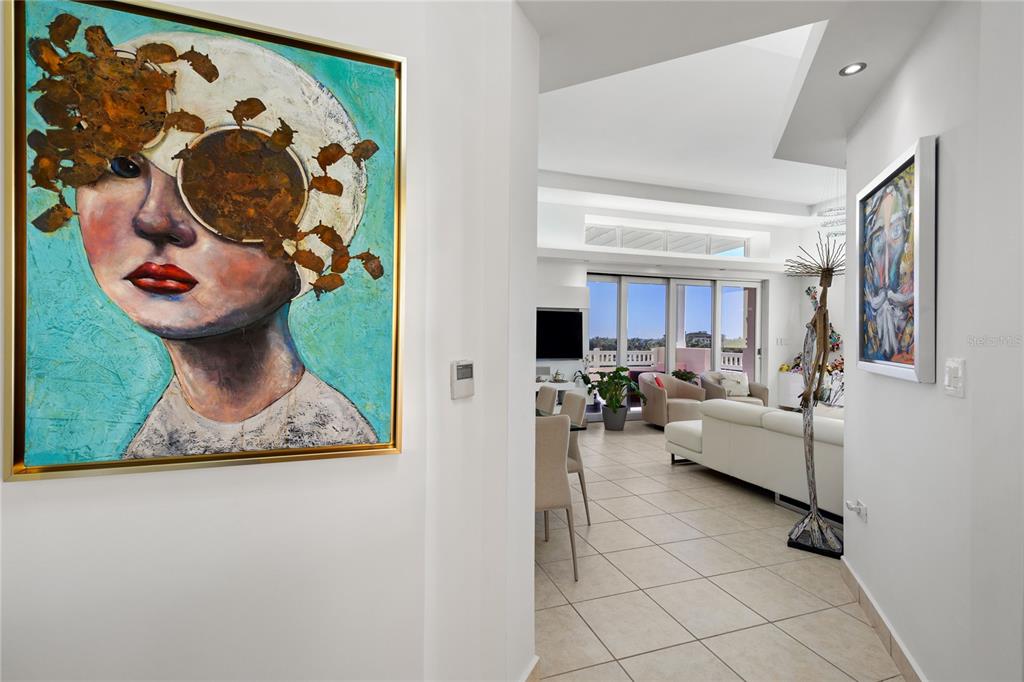 A hallway with two paintings leads into a bright living area with tile flooring — 100 OCEAN DRIVE UNIT 154, HUMACAO, PR