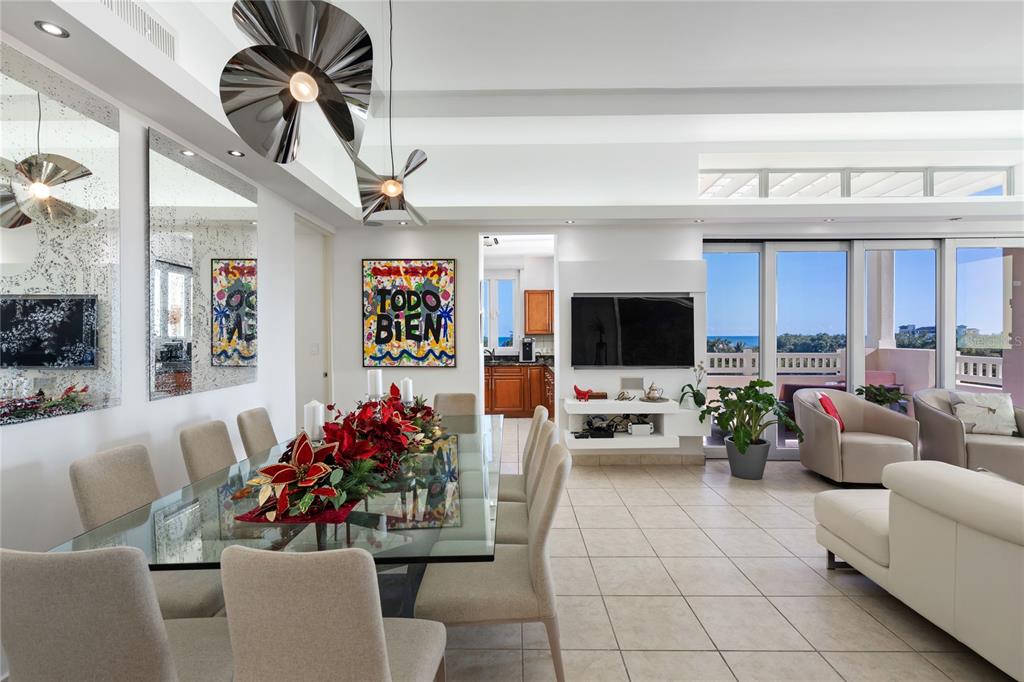 A bright, open-concept dining and living area features a glass table, modern lighting, and ocean views — 100 OCEAN DRIVE UNIT 154, HUMACAO, PR