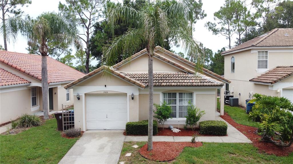 An exterior view of a single-story beige house with a tiled roof and palm trees — 2464 SAINT AUGUSTINE BOULEVARD, HAINES CITY, FL