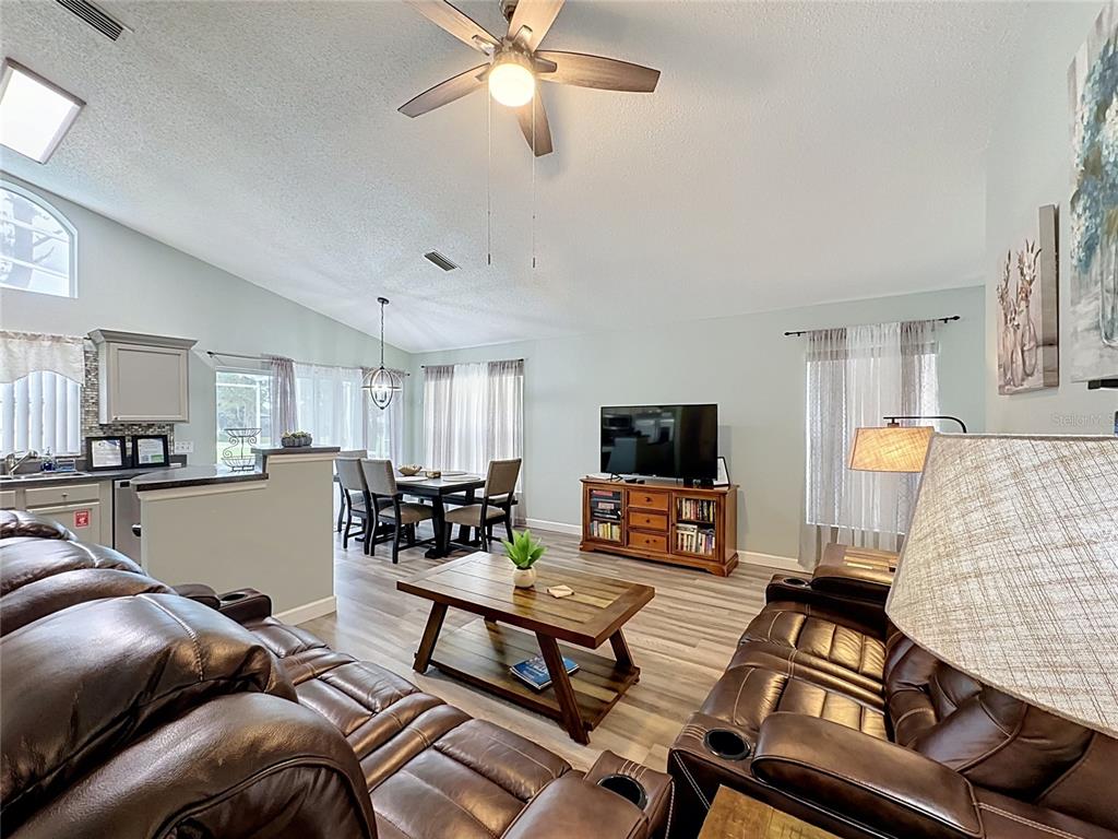 A living room with leather furniture, a wooden coffee table, and an adjacent dining area — 2464 SAINT AUGUSTINE BOULEVARD, HAINES CITY, FL