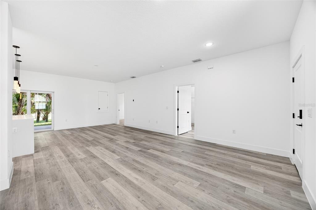 An open-concept living area features white walls, light wood-look flooring, and a sliding glass door — 3288 TISHMAN AVENUE, NORTH PORT, FL