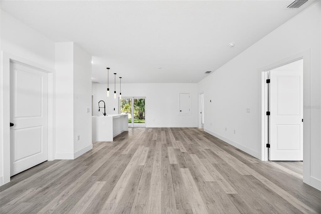 An open-concept living area features white walls, light wood-look flooring, and a kitchen island — 3288 TISHMAN AVENUE, NORTH PORT, FL