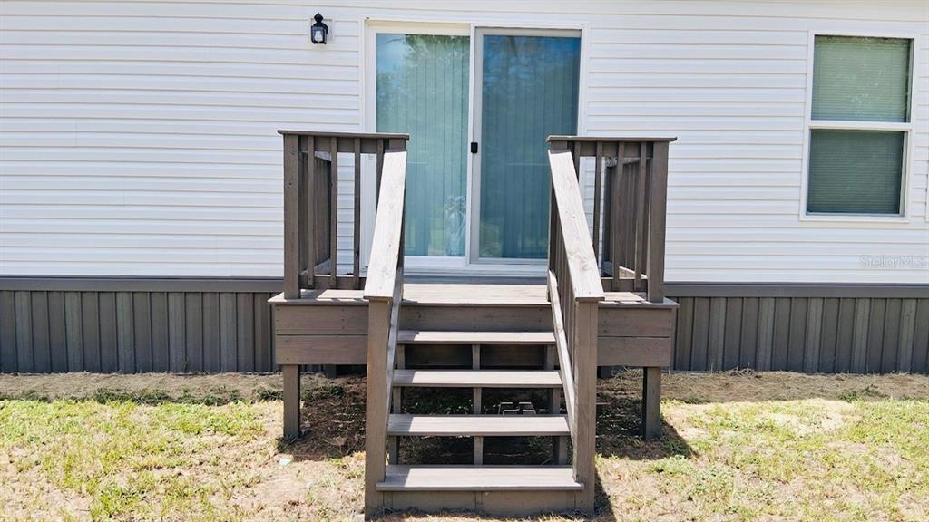 A wooden staircase leads to a sliding glass door on the exterior of a house — 6710 AUTUMNWOOD COURT, KEYSTONE HEIGHTS, FL
