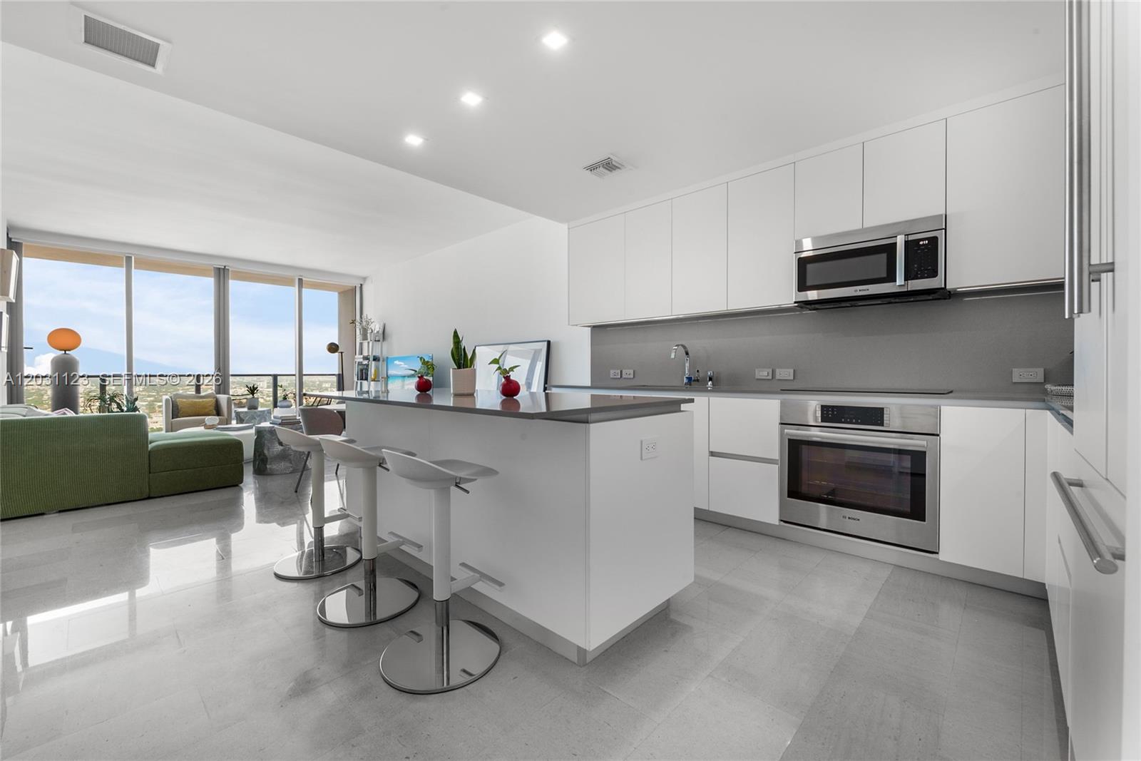 A modern kitchen features white cabinetry, stainless steel appliances, and a central island with stools — 88 SW 7th St # 3208, Miami FL 33130, MIAMI, FL