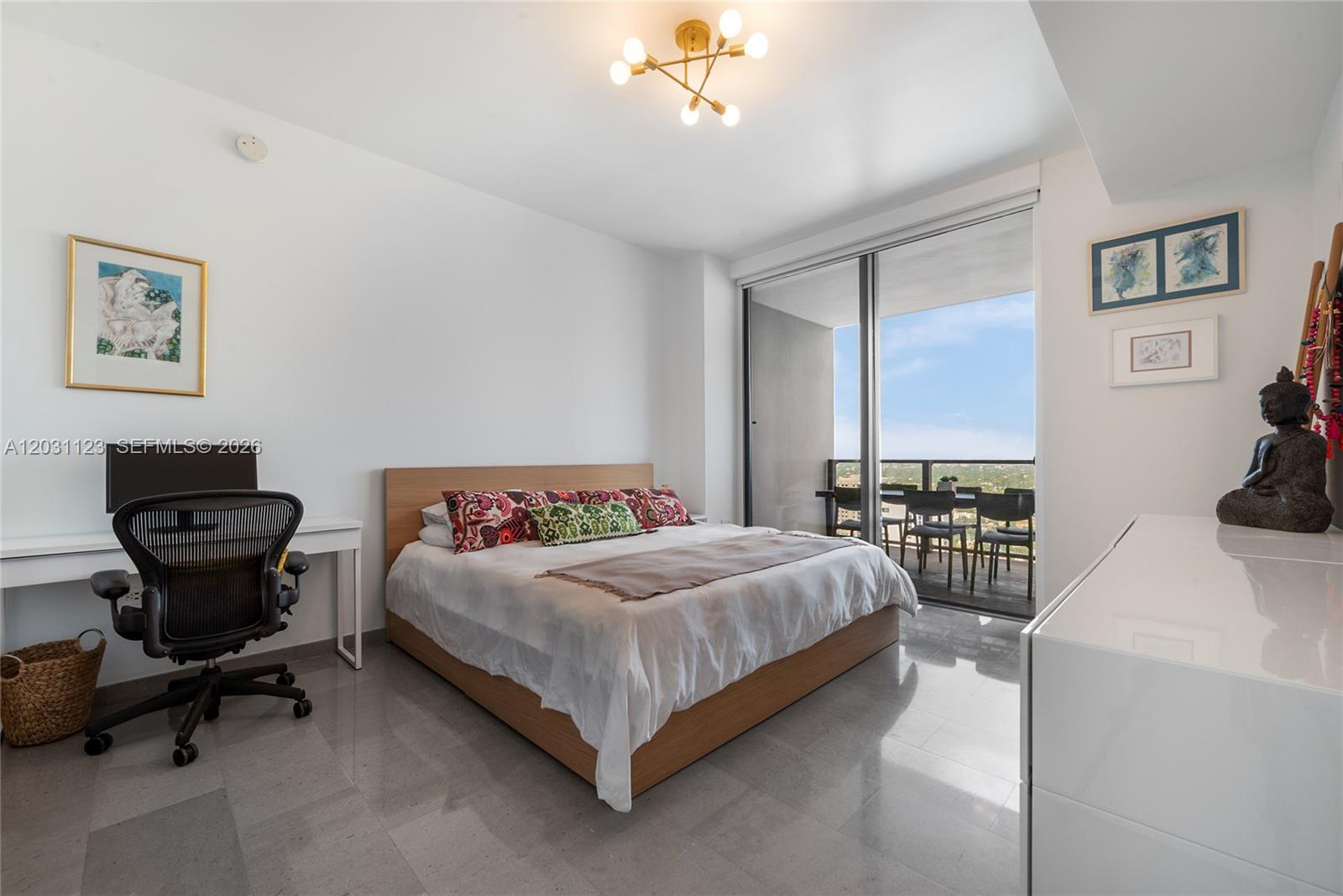 A bedroom with a platform bed, desk, and balcony access overlooking a city view — 88 SW 7th St # 3208, Miami FL 33130, MIAMI, FL