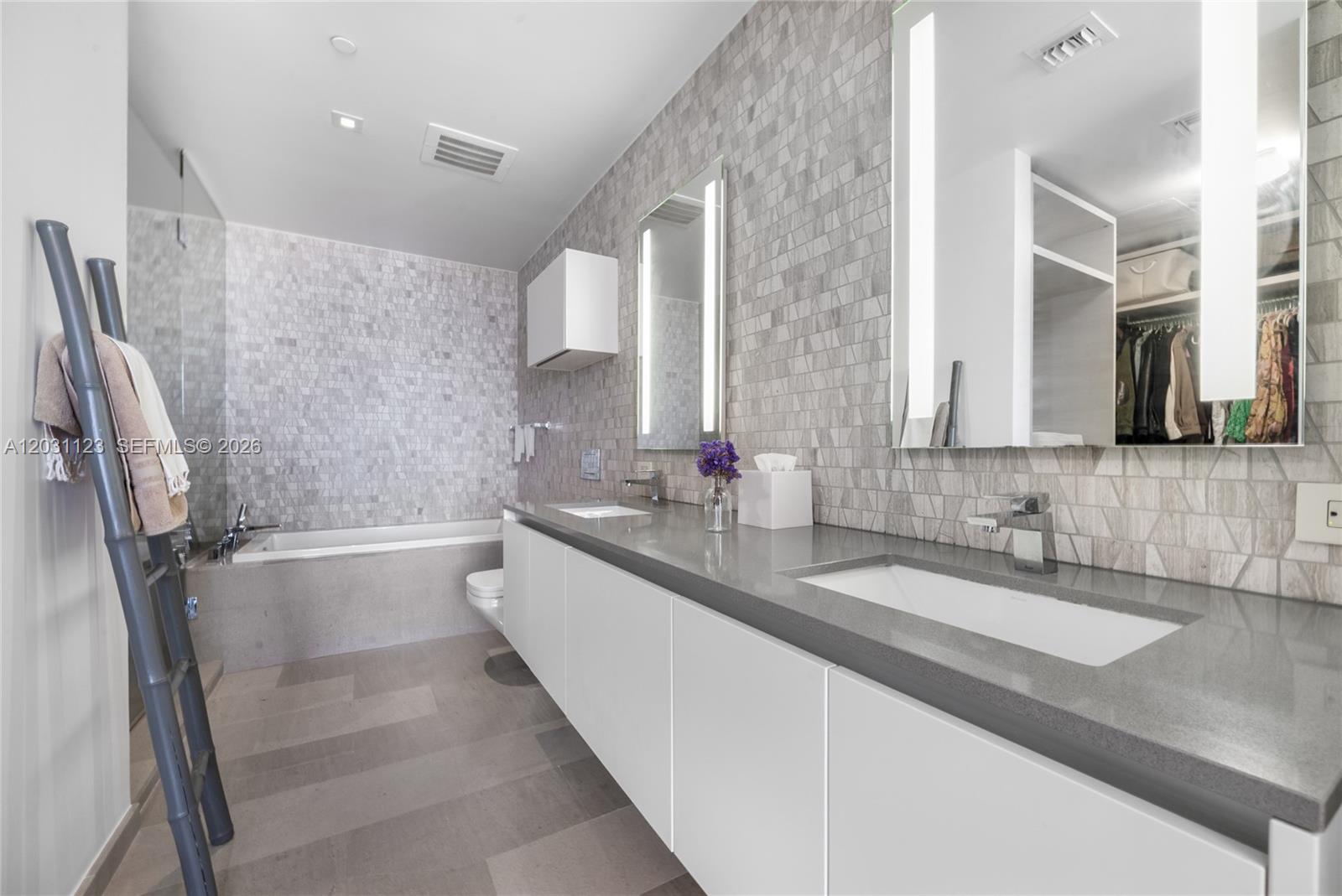 A modern bathroom features a double vanity with gray countertops and a tiled accent wall — 88 SW 7th St # 3208, Miami FL 33130, MIAMI, FL