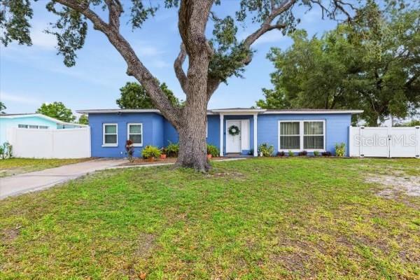 A blue single-story house features a large tree in the front yard and white fencing — 4601 N EMERALD AVENUE, TAMPA, FL