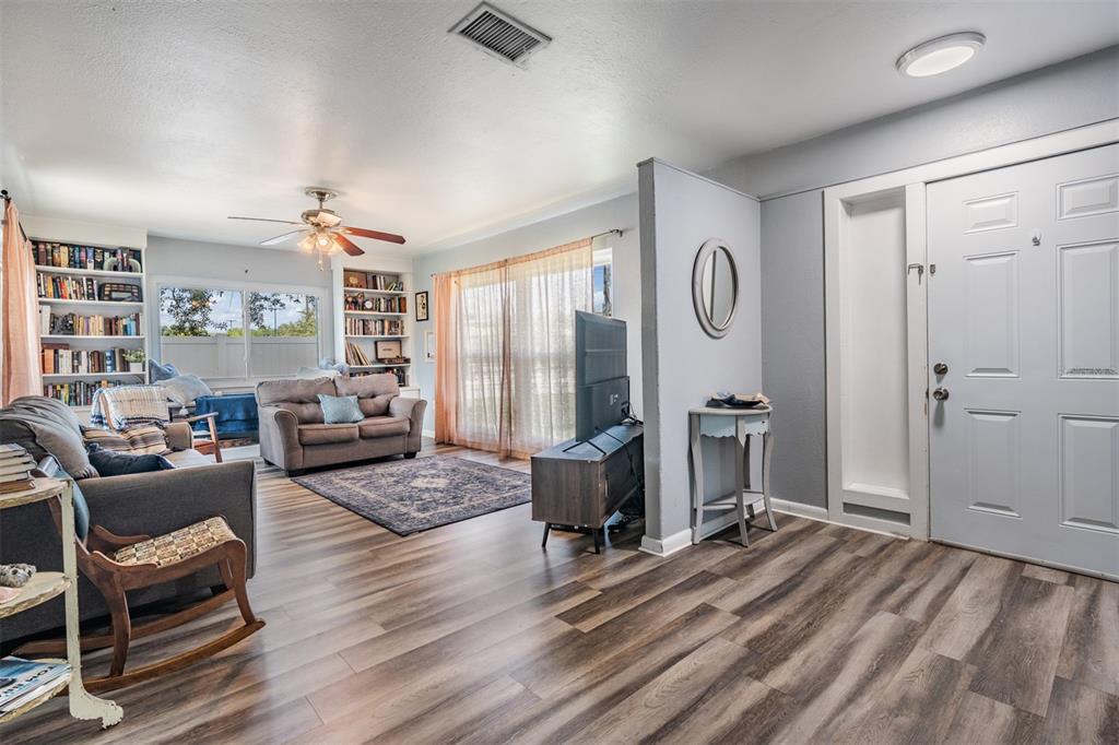 A living room features wood-look flooring, a ceiling fan, built-in bookshelves, and a front door — 4601 N EMERALD AVENUE, TAMPA, FL