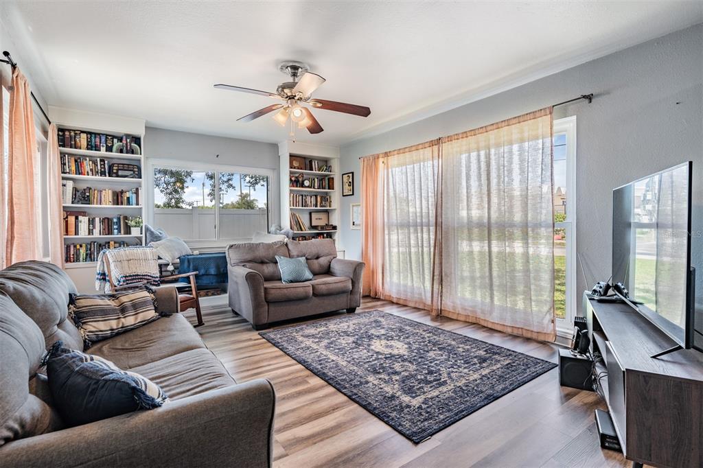 A living room features gray sofas, a patterned area rug, built-in bookshelves, and large windows — 4601 N EMERALD AVENUE, TAMPA, FL