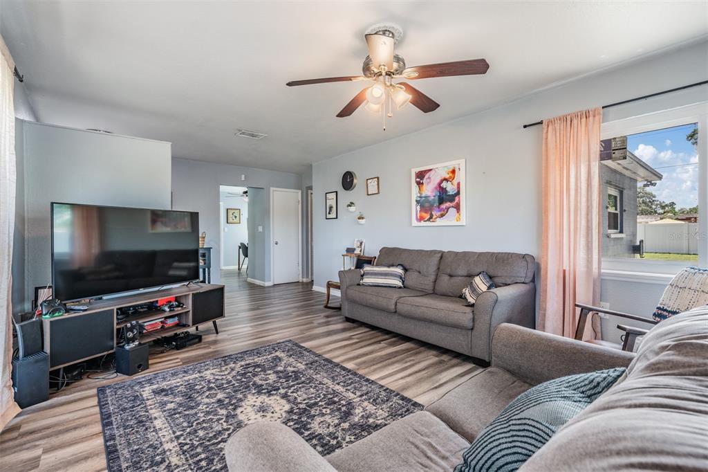 A living room features gray sofas, a television on a media console, and wood-look flooring — 4601 N EMERALD AVENUE, TAMPA, FL