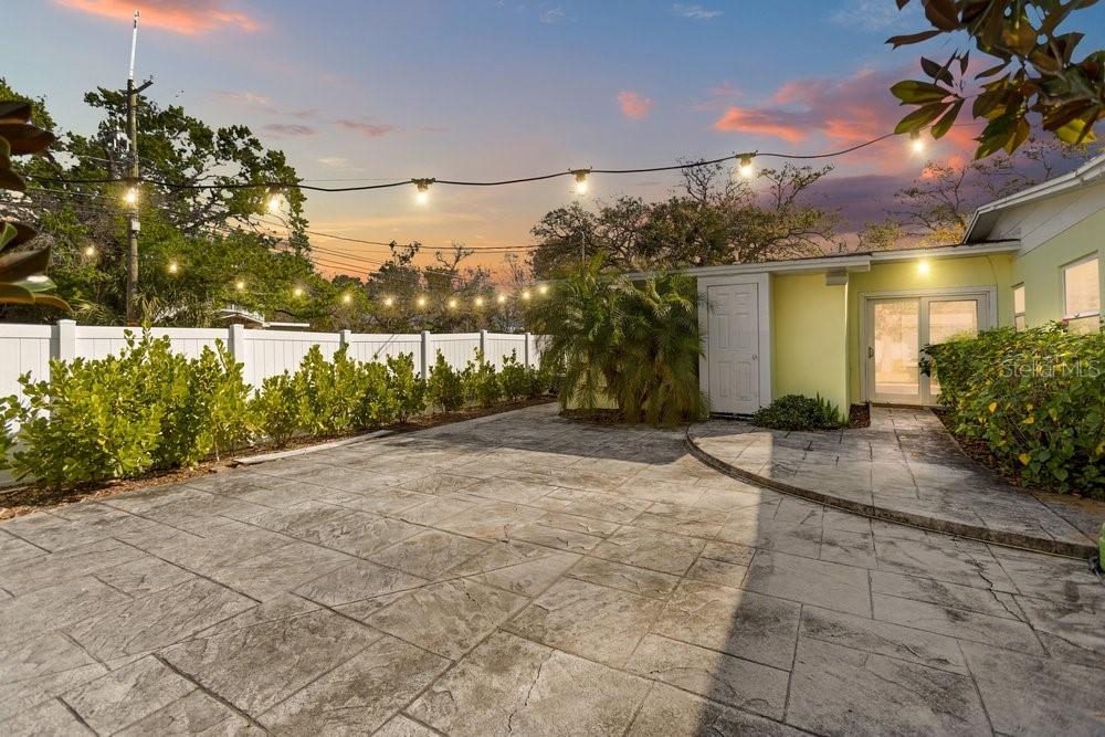 A paved patio area features string lights, a white fence, and a yellow house exterior — 201 S SHERRILL STREET, TAMPA, FL