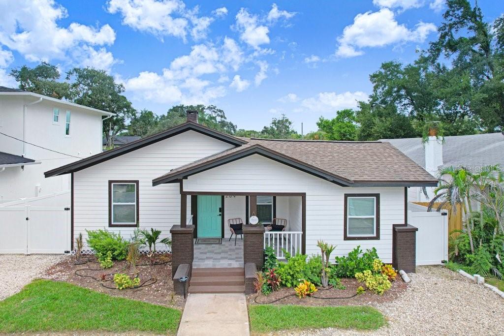 A single-story house with white siding, a brown roof, and a front porch with brick pillars — 209 W HIAWATHA STREET, TAMPA, FL
