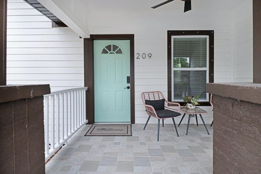 A covered front porch features a light blue door, a window, and patio furniture — 209 W HIAWATHA STREET, TAMPA, FL