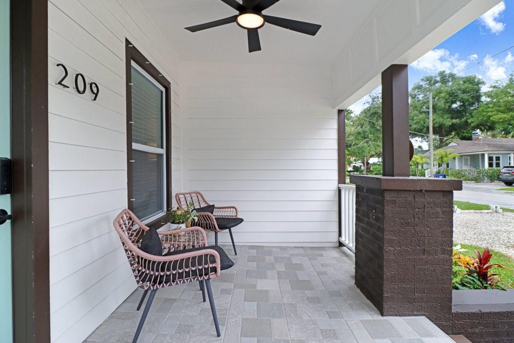 A covered front porch features white horizontal siding, a ceiling fan, and two wicker chairs — 209 W HIAWATHA STREET, TAMPA, FL