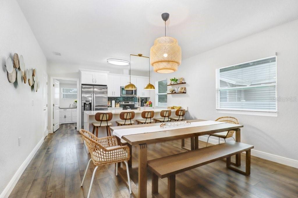 A dining area with a wooden table and bench, adjacent to a kitchen with bar seating — 209 W HIAWATHA STREET, TAMPA, FL