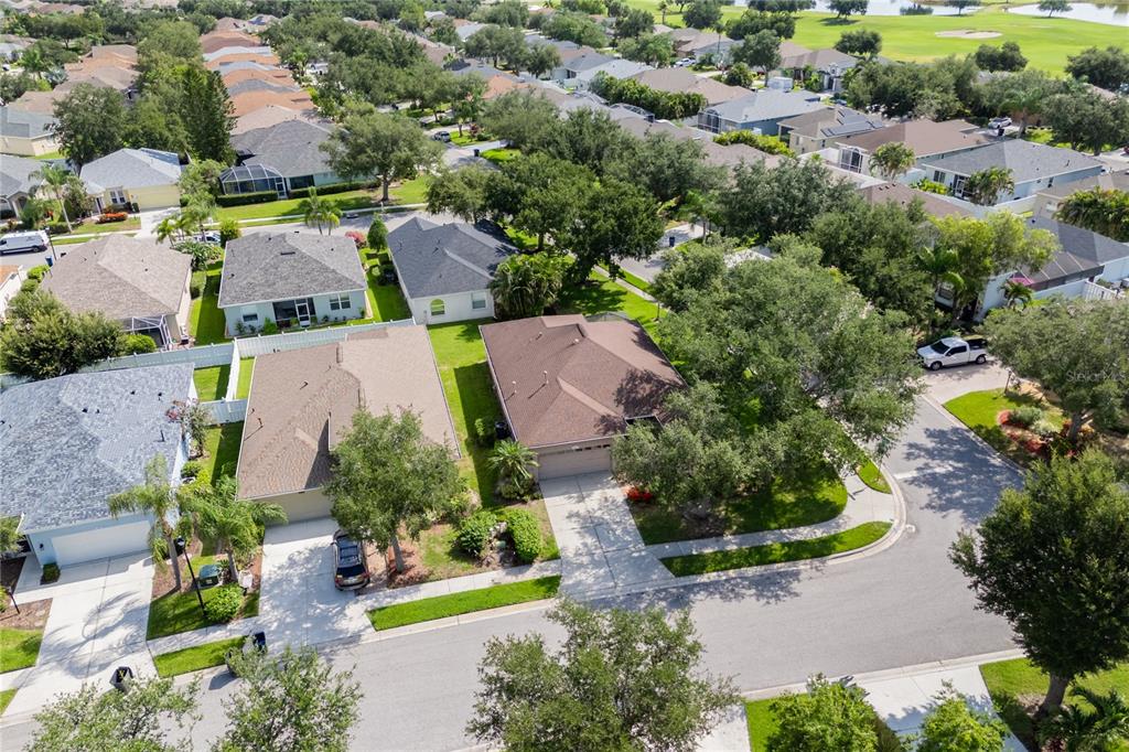 An aerial view shows two suburban houses with brown roofs and driveways on a residential street — 1415 MILLBROOK CIRCLE, BRADENTON, FL