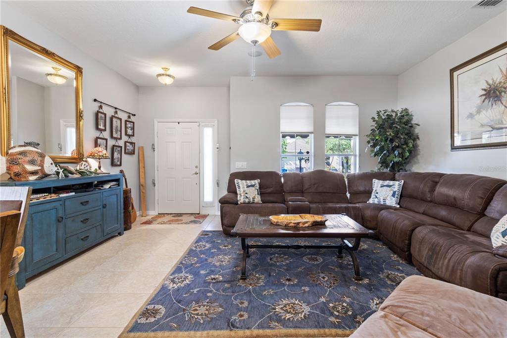 A living room features a brown sectional sofa, a blue area rug, and a blue sideboard — 1415 MILLBROOK CIRCLE, BRADENTON, FL