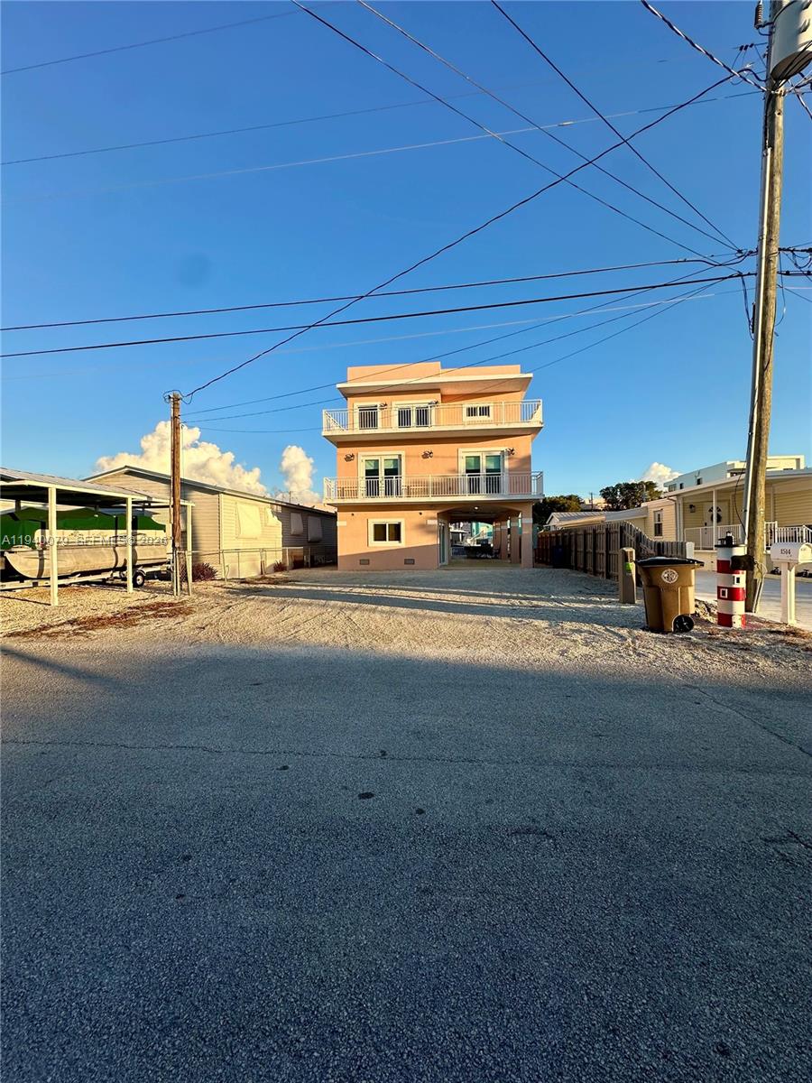 An aerial view shows a three-story pink house with balconies, a boat, and a tiki hut — 1516 Aqueduct Ln # 1, Key Largo FL 33037, KEY LARGO, FL