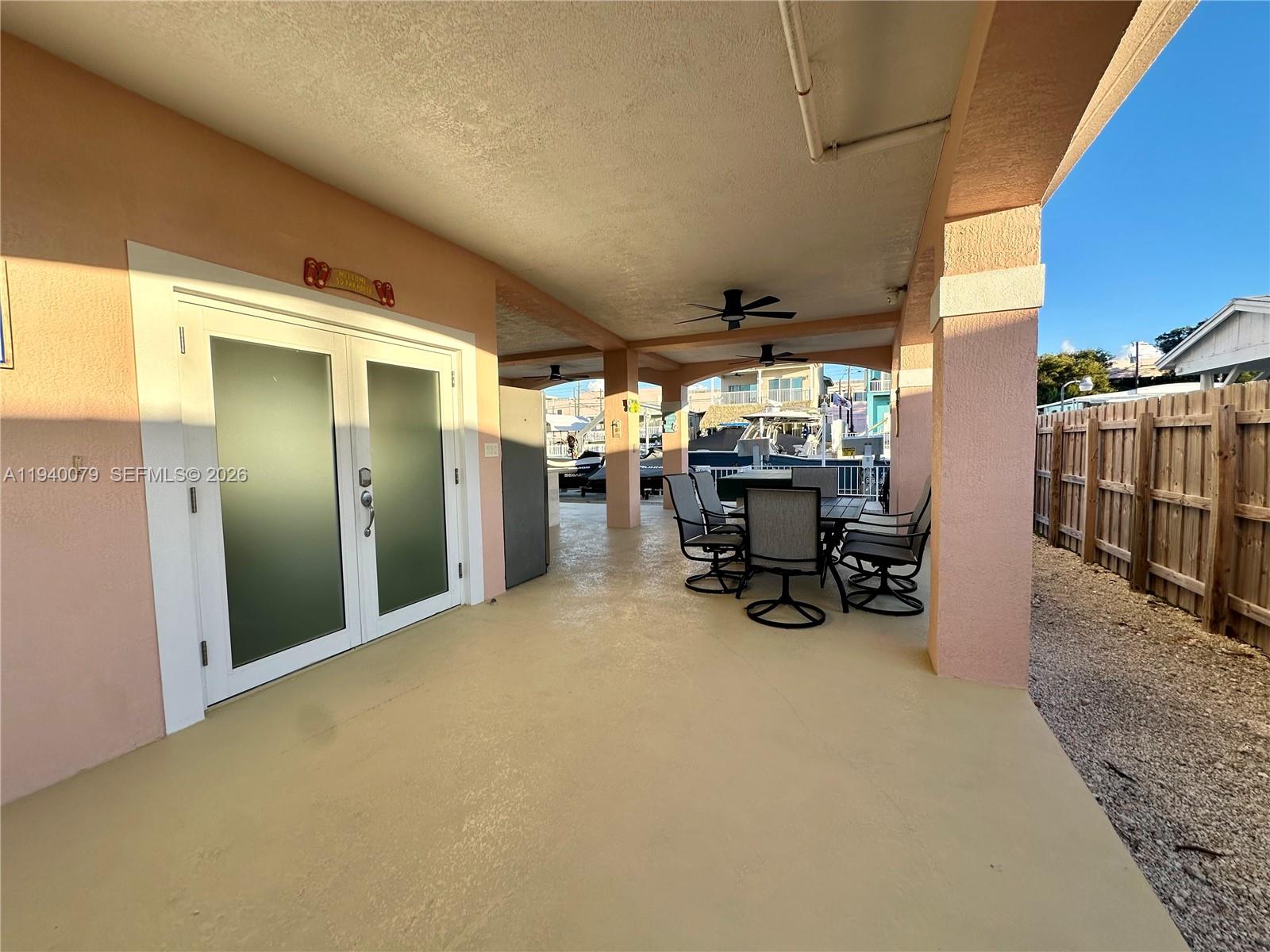 A covered patio with peach-colored walls and arched columns sits beside a gravel driveway — 1516 Aqueduct Ln # 1, Key Largo FL 33037, KEY LARGO, FL