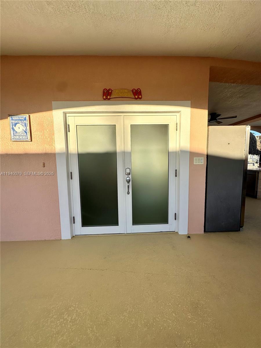 A covered outdoor patio features a dining set, ceiling fans, and double glass doors — 1516 Aqueduct Ln # 1, Key Largo FL 33037, KEY LARGO, FL