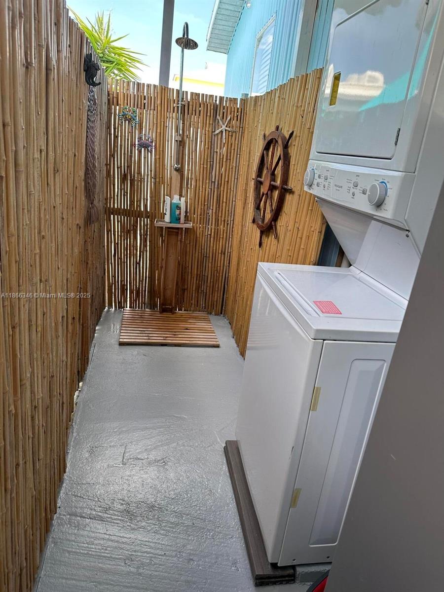 An outdoor shower area features bamboo walls, a wooden floor mat, and a stacked laundry unit — 325 Calusa St #499, Key Largo FL 33037, KEY LARGO, FL