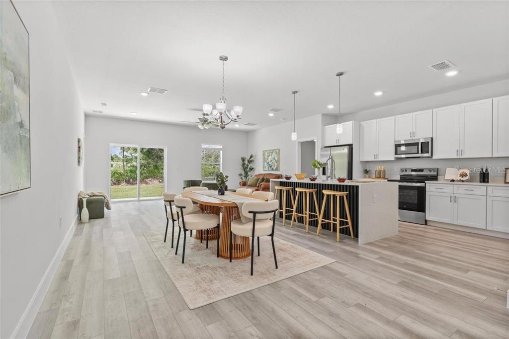 An open-concept kitchen and dining area features white cabinetry, a kitchen island, and wood flooring — 3830 GARDENIA DRIVE, INDIAN LAKE ESTATES, FL