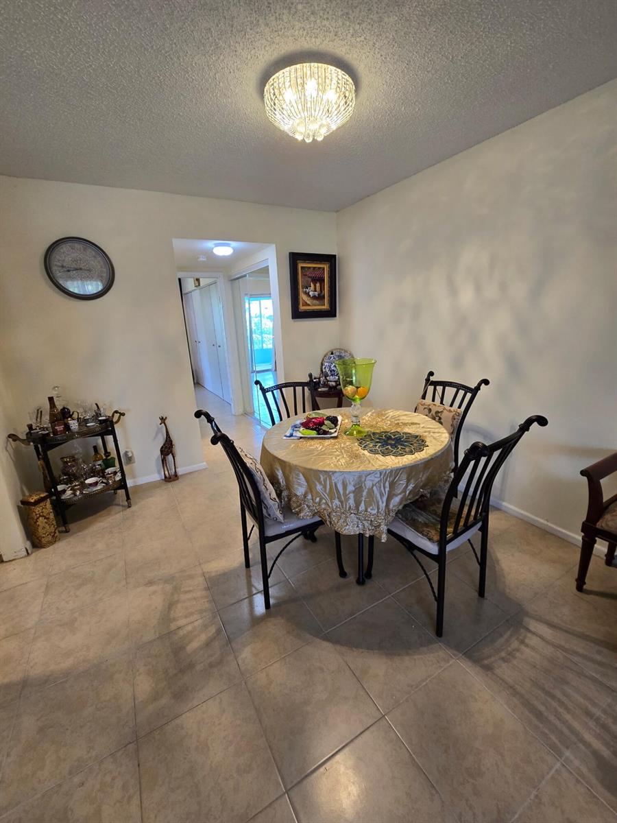 A dining area features a round table with a gold tablecloth, four chairs, and tile flooring — 12 Prescott # 12, Deerfield Beach FL 33442, DEERFIELD BEACH, FL