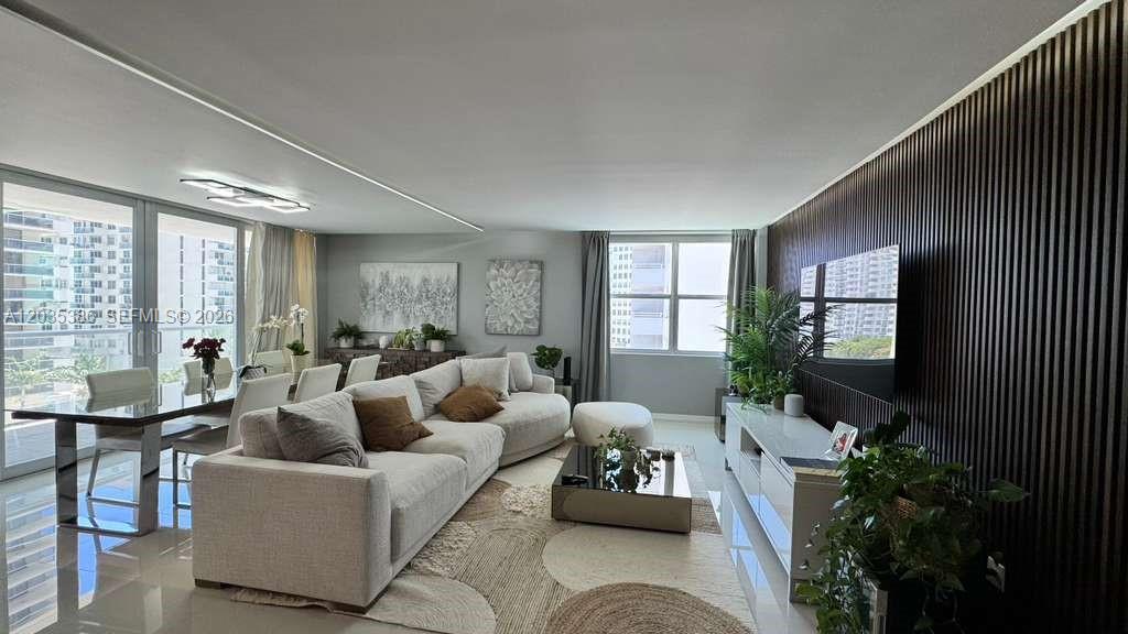 A modern living room features a large sectional sofa, a dining area, and slatted wall paneling — 5750 Collins Ave # 7A, Miami Beach FL 33140, MIAMI BEACH, FL