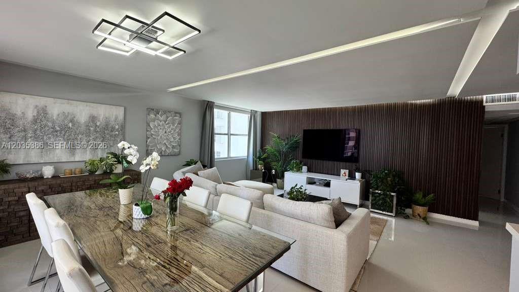 A dining and living area features a wood-slat accent wall, modern lighting, and neutral furniture — 5750 Collins Ave # 7A, Miami Beach FL 33140, MIAMI BEACH, FL