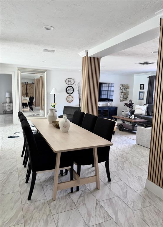 A dining area with a light wood table and black chairs sits before a living room — 4534 N LAKE DRIVE, SARASOTA, FL