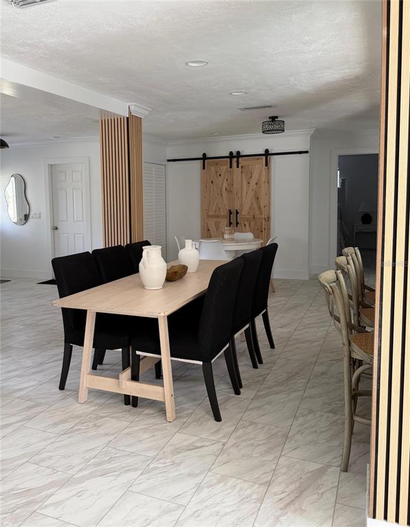A dining area features a light wood table with black chairs and sliding barn doors — 4534 N LAKE DRIVE, SARASOTA, FL