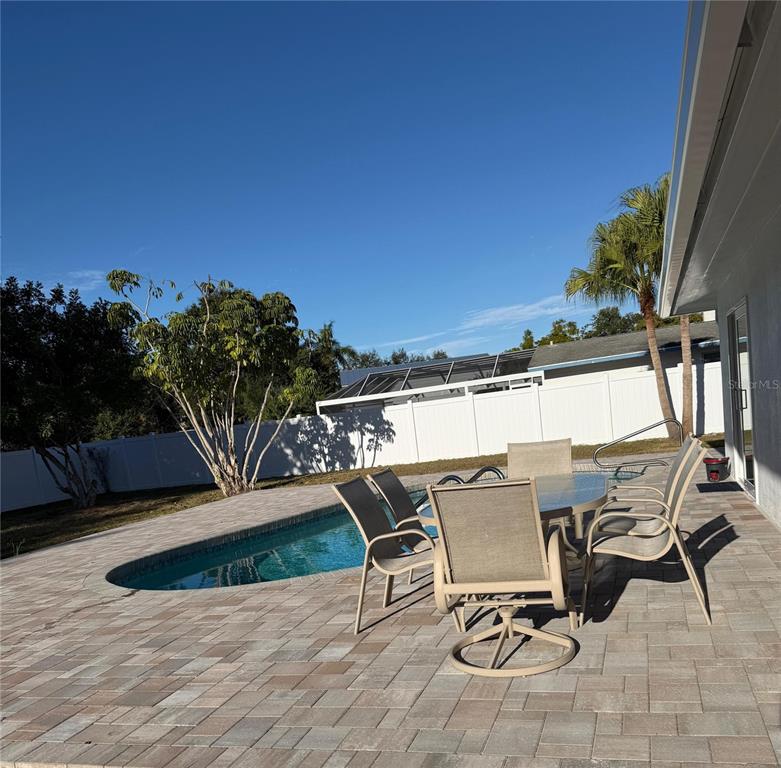 A backyard patio features a swimming pool, dining set, and a white privacy fence — 4534 N LAKE DRIVE, SARASOTA, FL