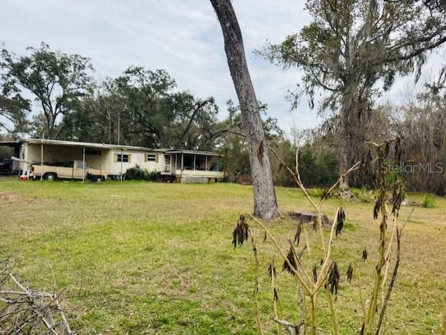 A single-story mobile home sits on a grassy lot with large trees and a truck — 11417 SW 42ND TERRACE, WEBSTER, FL