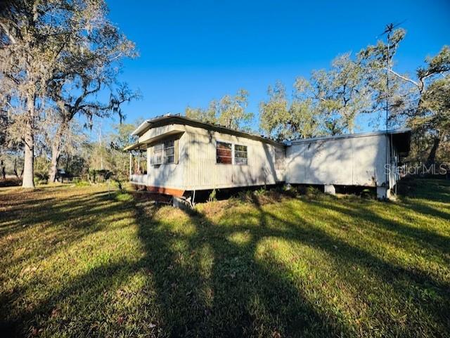 A weathered mobile home sits on a grassy lot surrounded by large, moss-covered trees — 11417 SW 42ND TERRACE, WEBSTER, FL