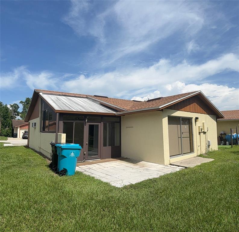 The exterior of a house features a screened-in porch, a concrete patio, and a blue bin — 1002 OROPESA AVENUE, ORLANDO, FL