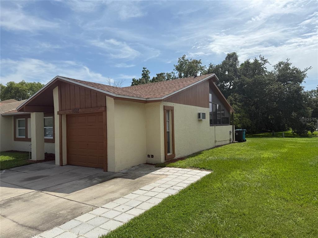 A single-story house with a tan stucco exterior, brown wood trim, and a one-car garage — 1002 OROPESA AVENUE, ORLANDO, FL