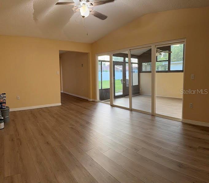 A living room with light wood-look flooring, a vaulted ceiling, and sliding glass doors — 1002 OROPESA AVENUE, ORLANDO, FL